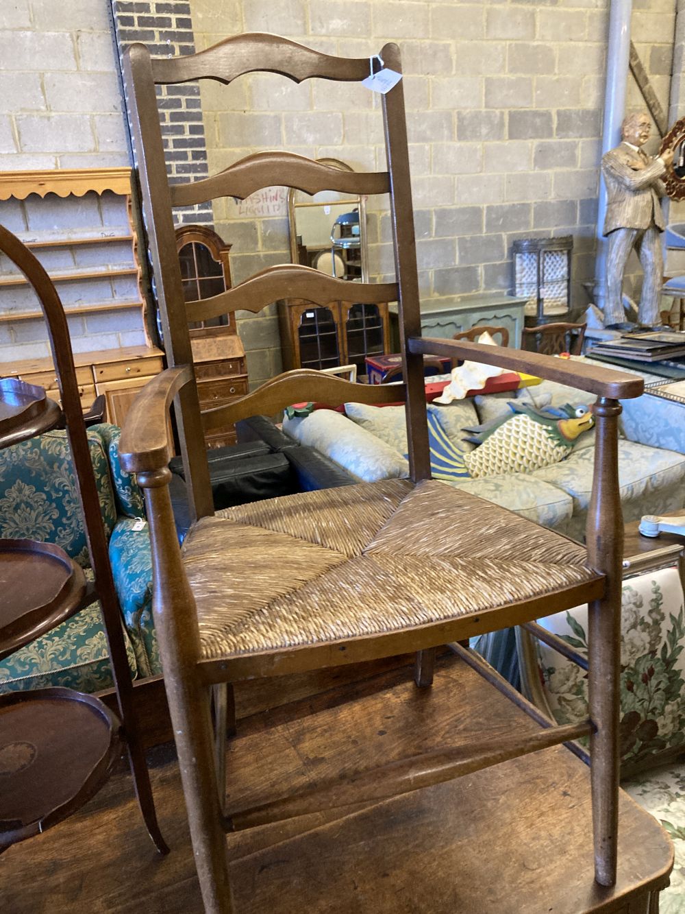 An Arts & Crafts ladder-back rush-seat elbow chair and an Edwardian inlaid mahogany three-tier cake stand (faults), 96cm high